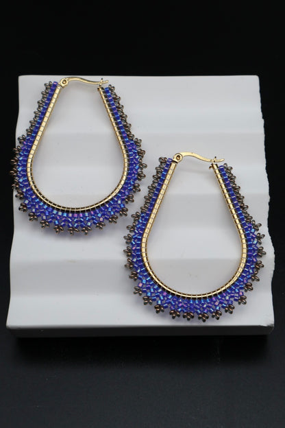 Pair of blue beaded earrings on a white stand with a black background