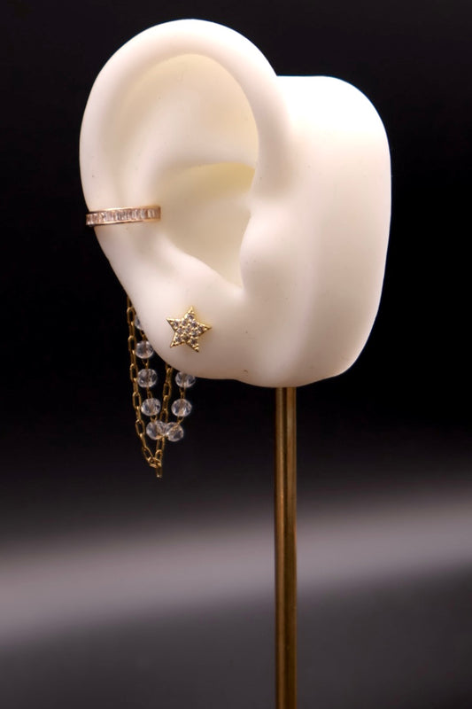 Earring displayed on a mannequin ear with a dark background