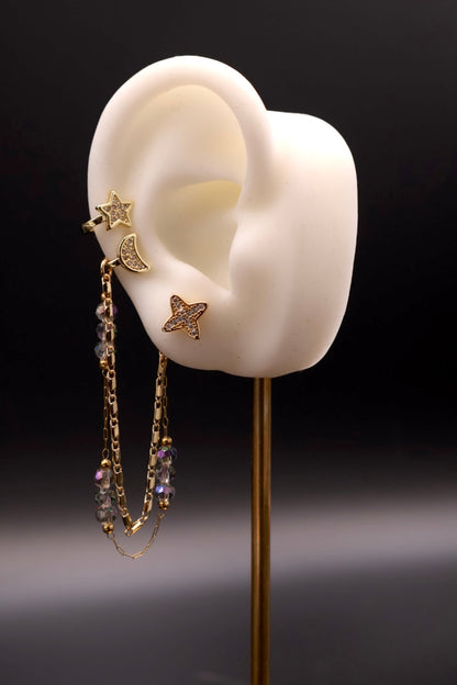 Gold earring with star and butterfly design on a white ear model against a dark background