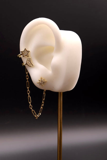 Gold earring with star and chain design on a white ear model against a black background