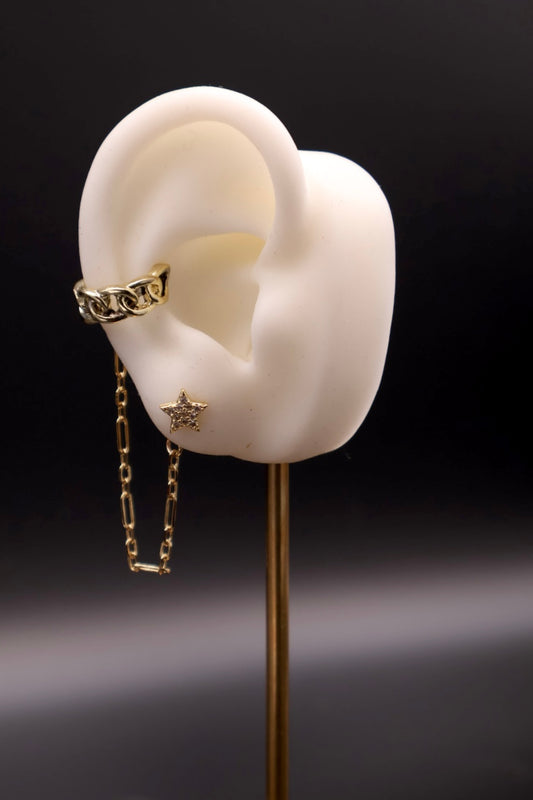 Gold chain earring on a white ear model with a dark background
