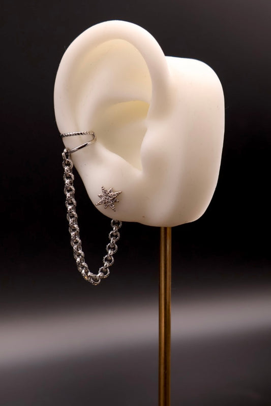Silver chain earring on a white ear model against a black background