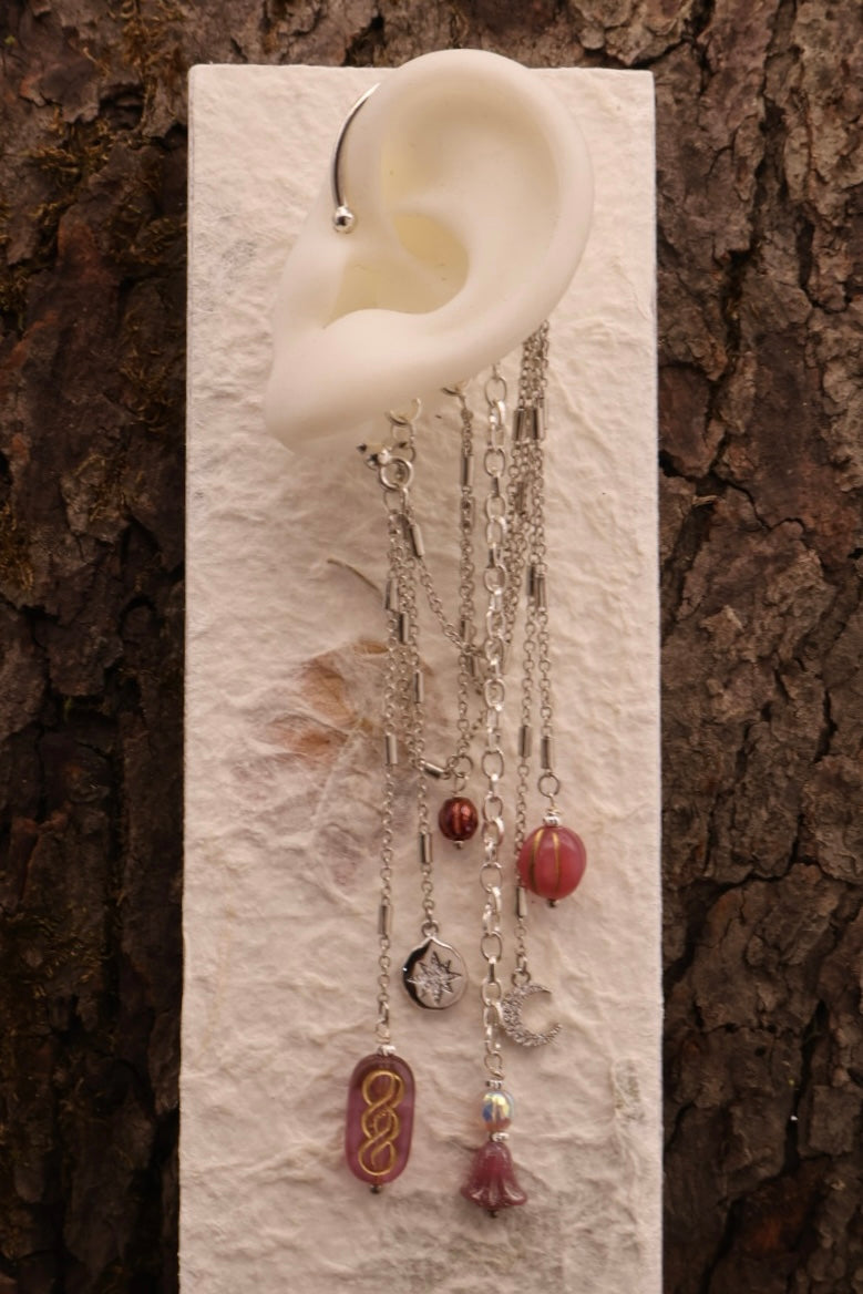 Earring displayed on a white ear model against a textured brown background