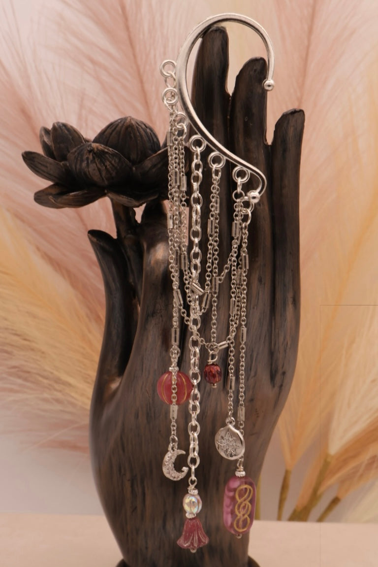 Set of silver chains with charms on a decorative stand against a neutral background