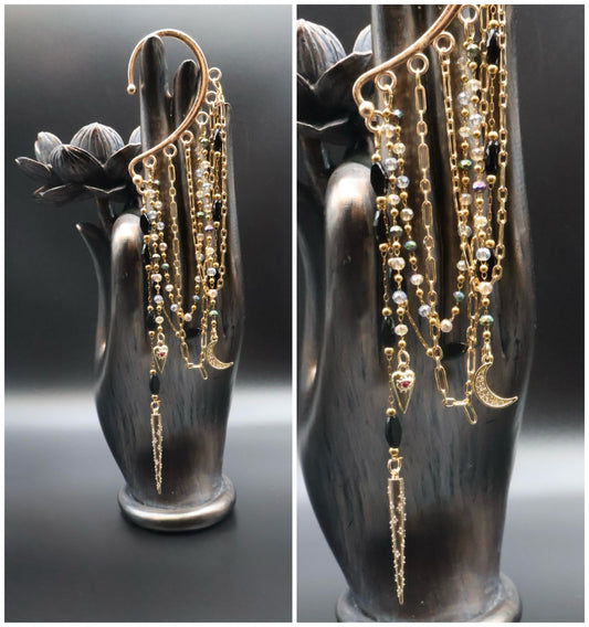 Gold chain earrings displayed on a black hand-shaped jewelry stand.