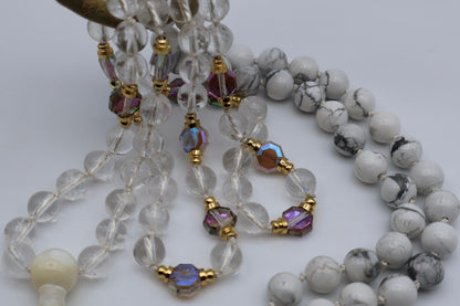 Two beaded necklaces with clear, white, and multicolored beads on a light background.
