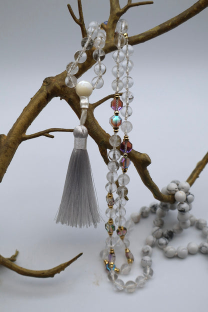 Beaded necklace with tassel on a branch against a white background