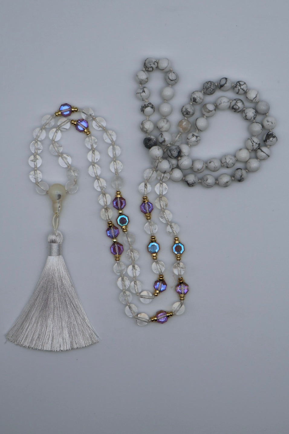 Two beaded necklaces with tassels on a gray background