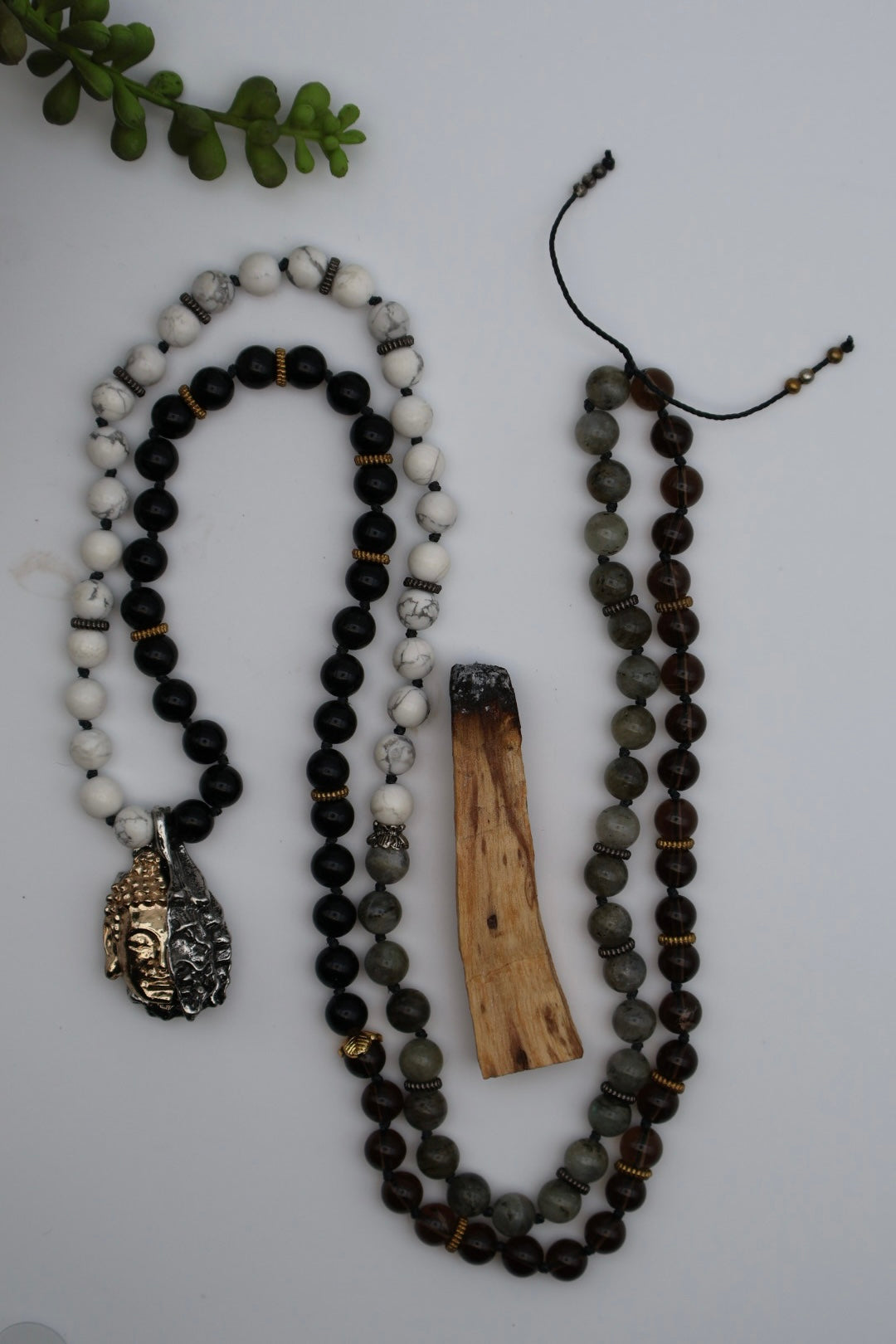 Two beaded necklaces with a wooden piece on a light gray background