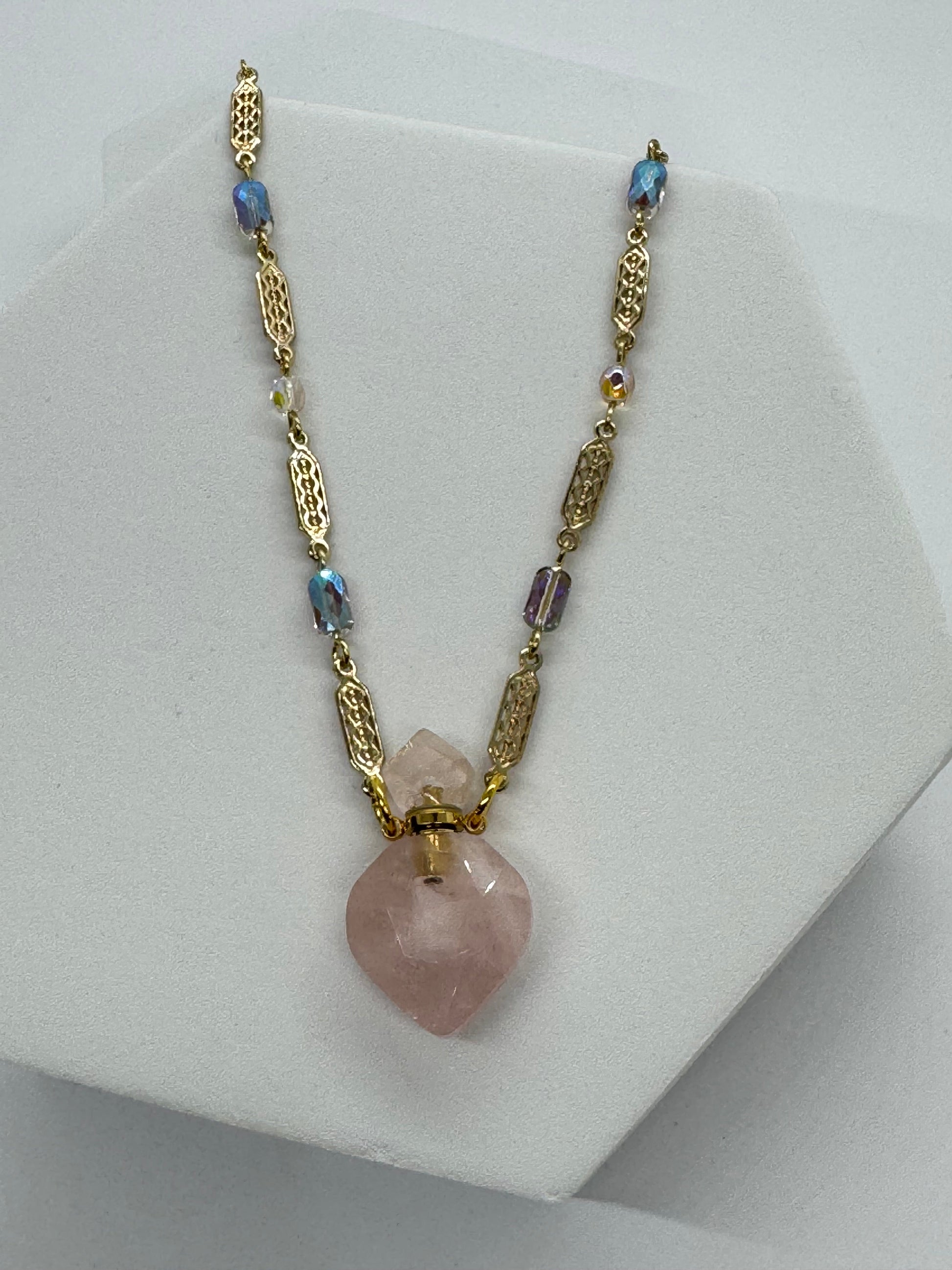 Necklace with a pink gemstone pendant on a white stand