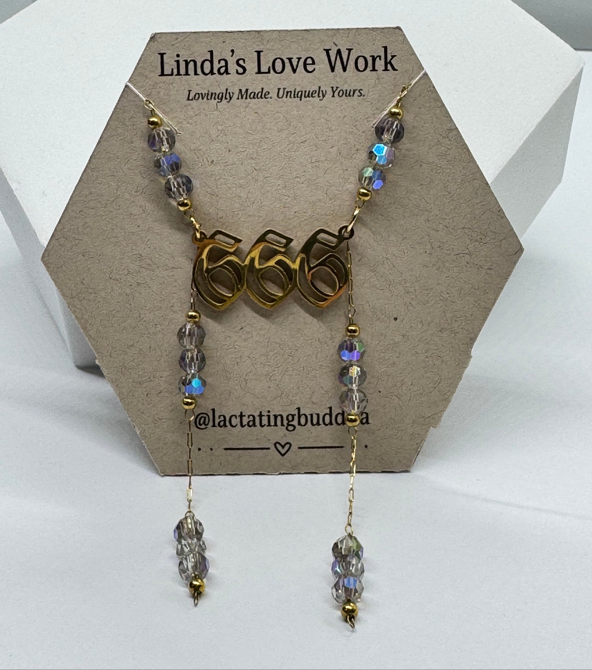 Necklace with '666' pendant and beaded chain on a branded card.