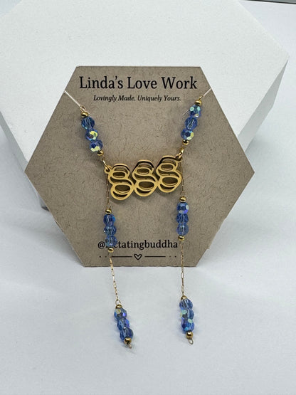 Necklace with blue beads and gold chain on a brown card with 'Linda's Love Work' text.