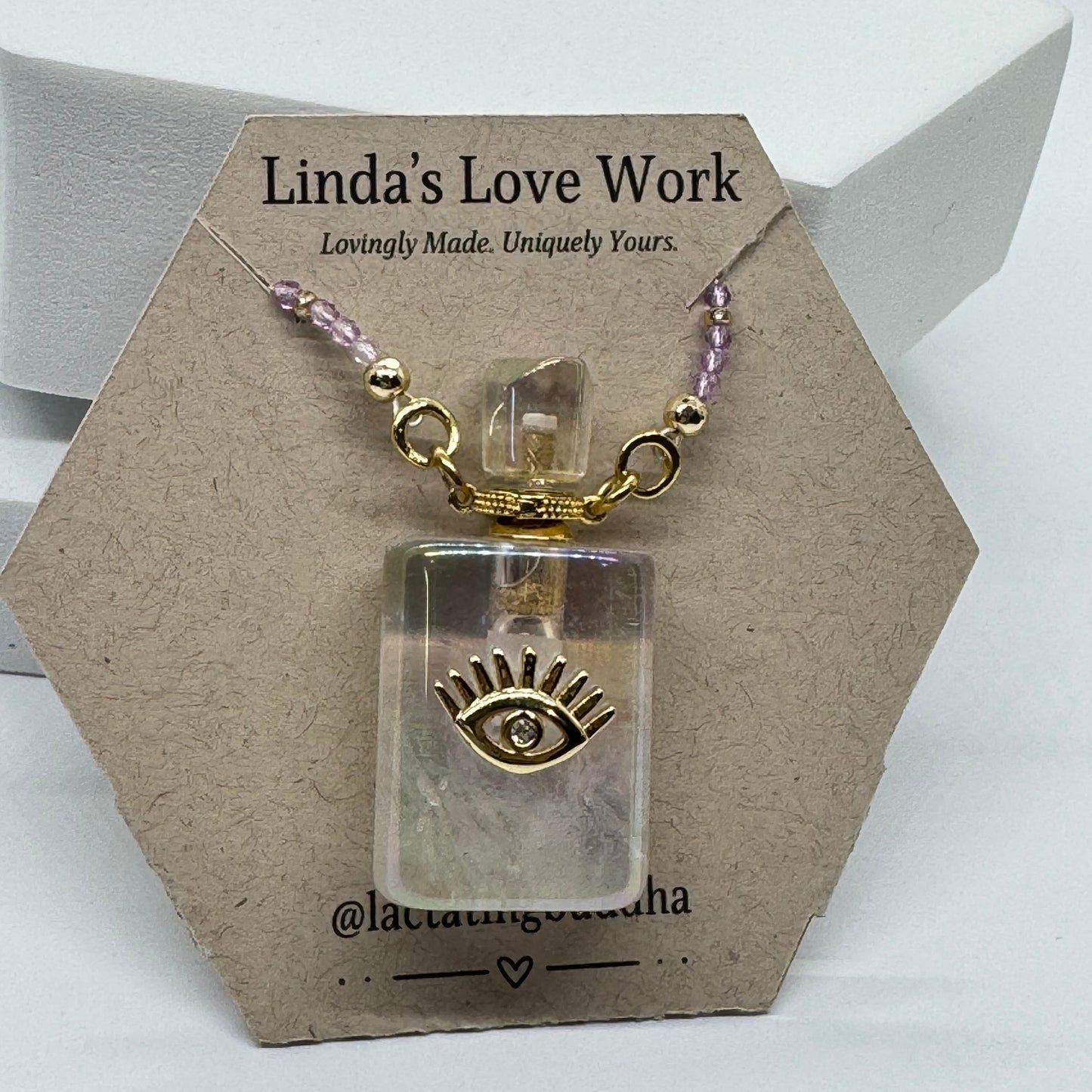 Small clear container with gold and purple accents on a branded card