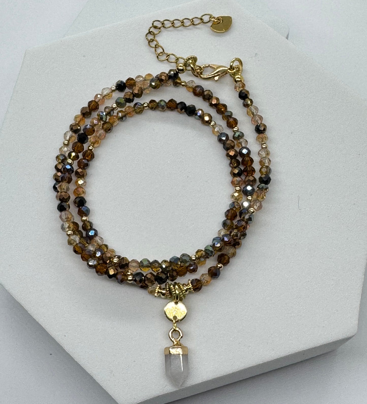 Beaded necklace with a white crystal pendant on a white stand