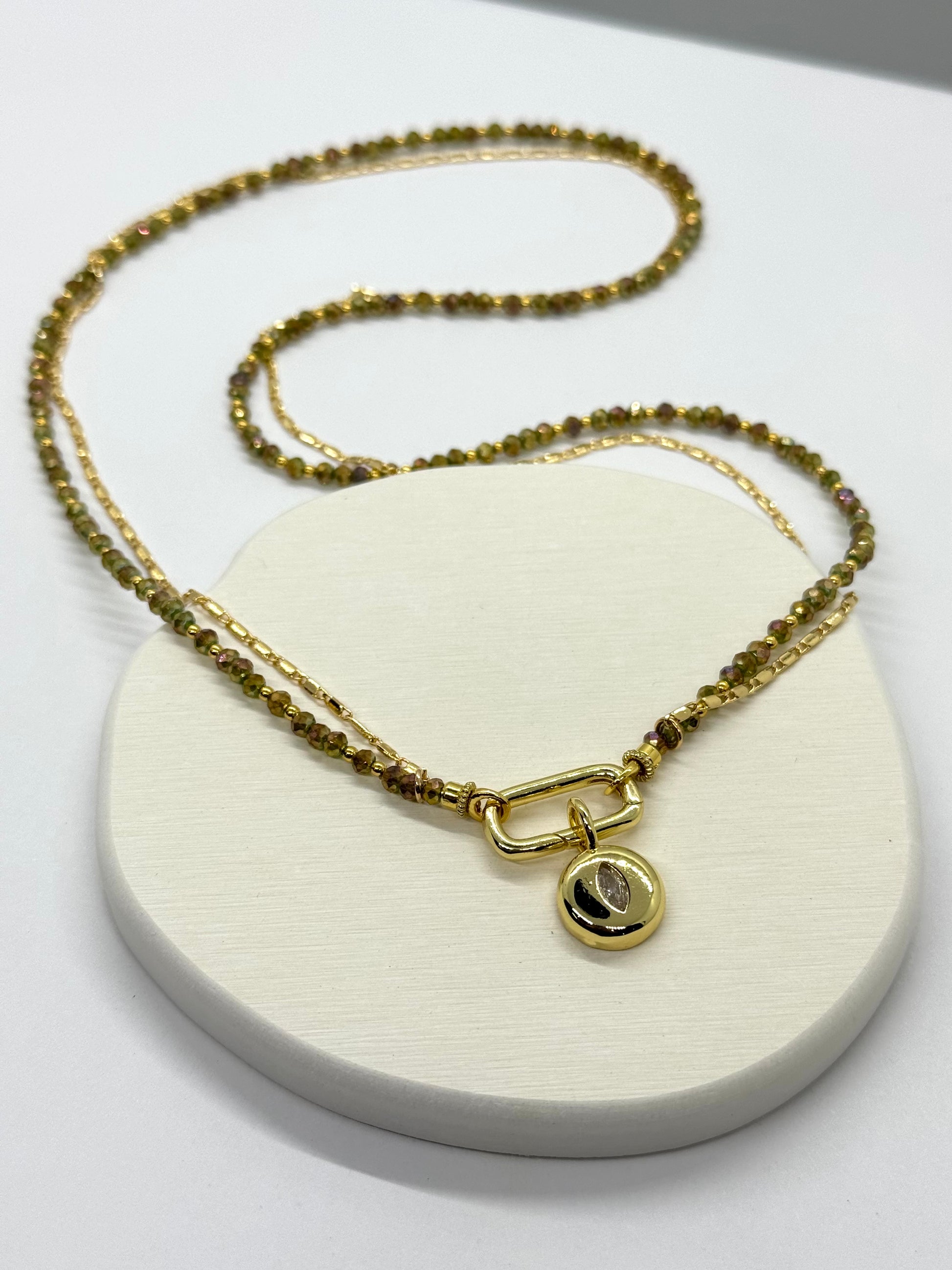 Gold necklace with a pendant on a white stand