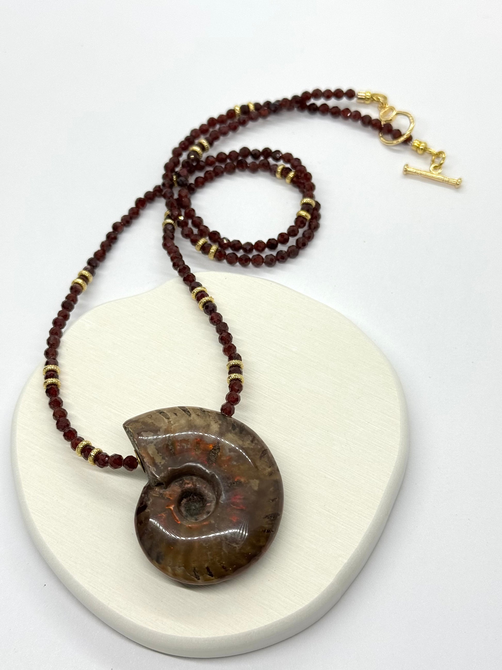 Necklace with a large ammonite fossil pendant on a white background