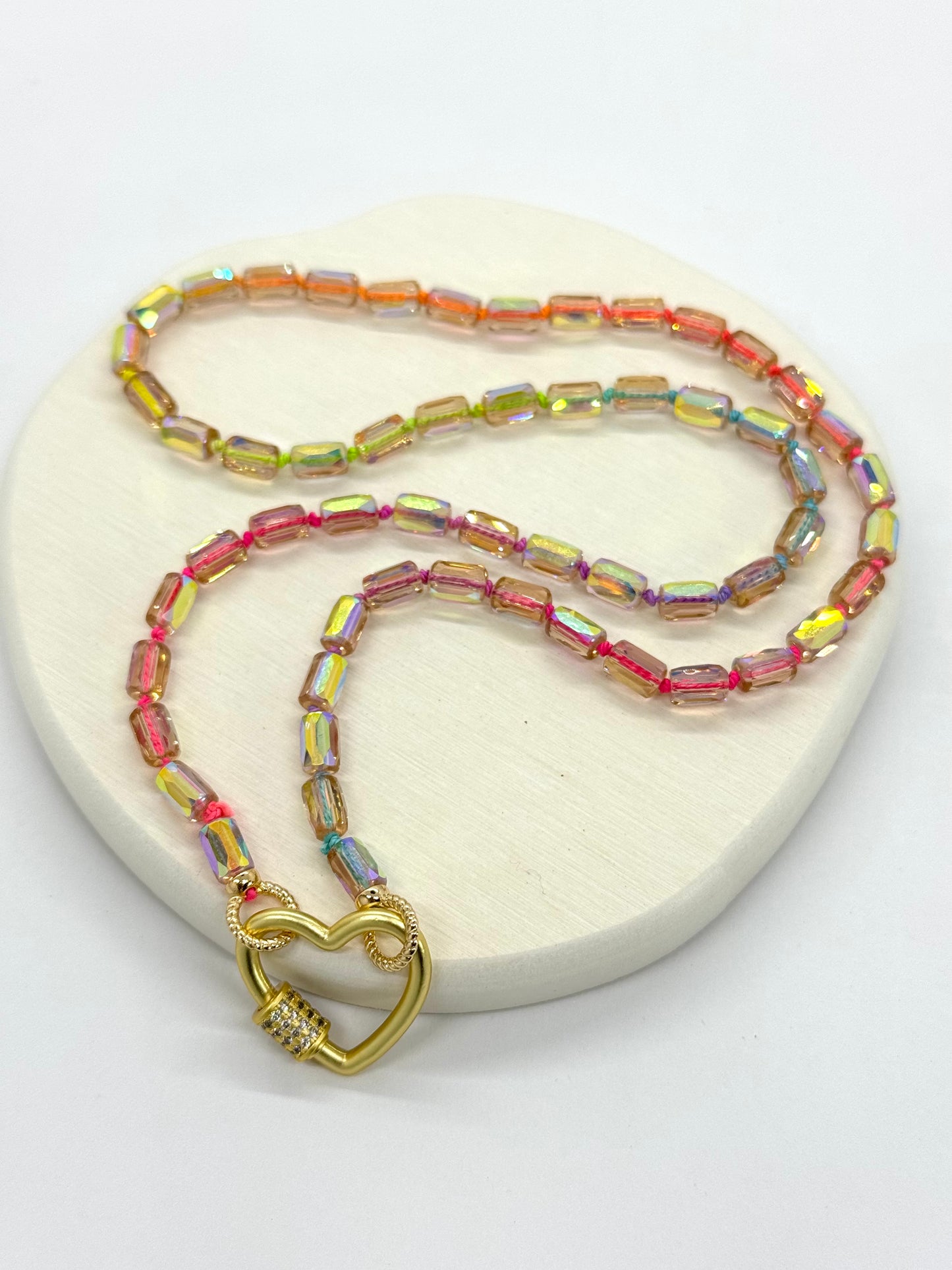 Necklace with multicolored beads and a gold heart-shaped clasp on a white background
