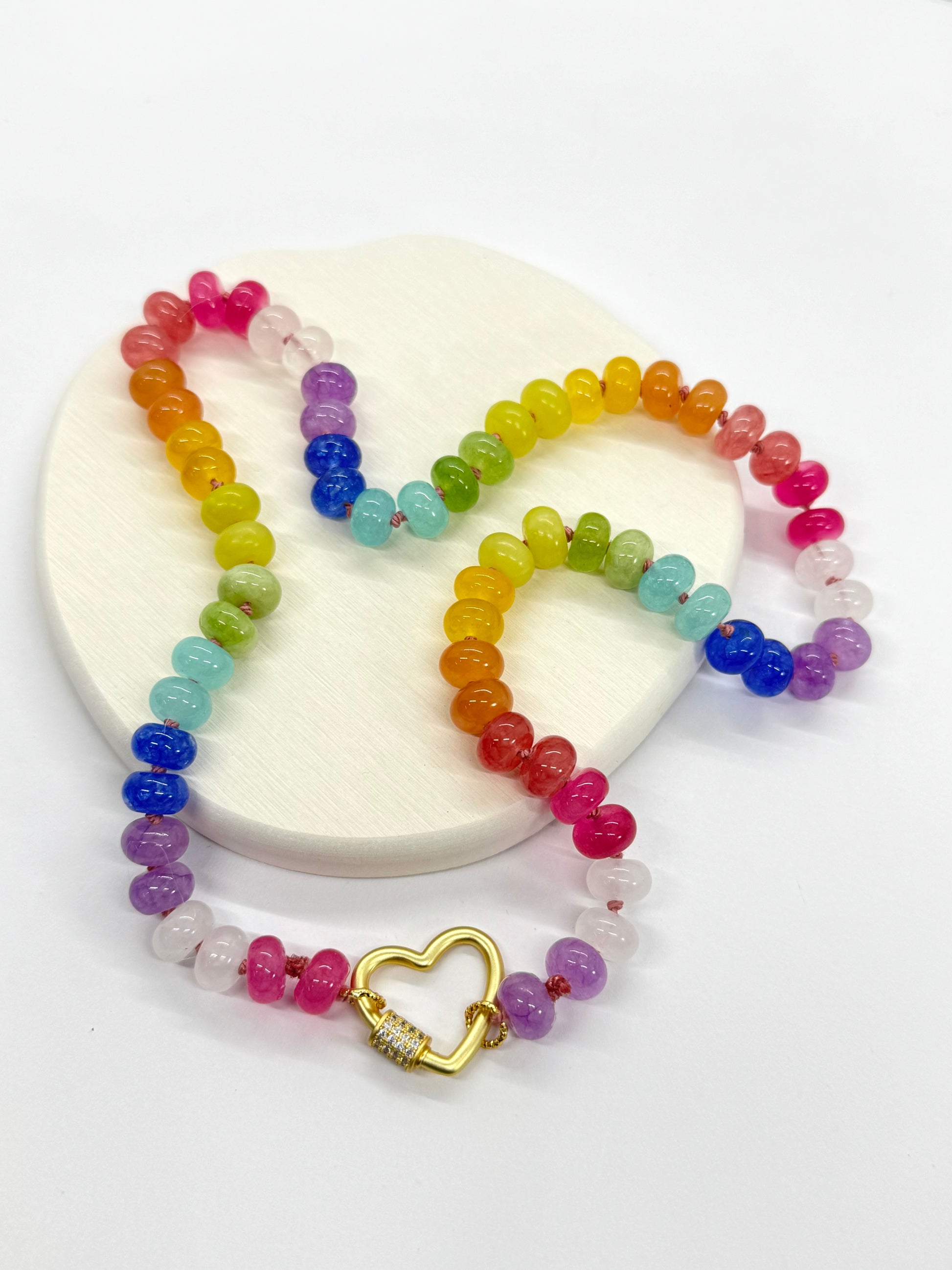 Colorful beaded necklace with a gold heart charm on a white background