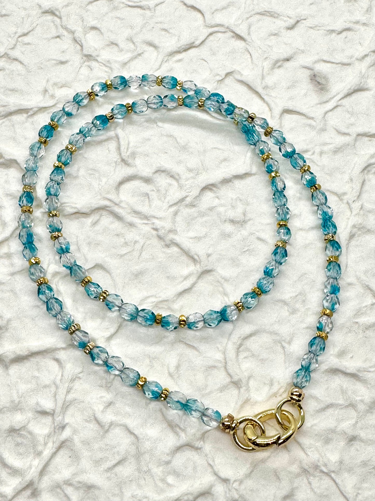 Beaded necklace with a gold clasp on a textured white background