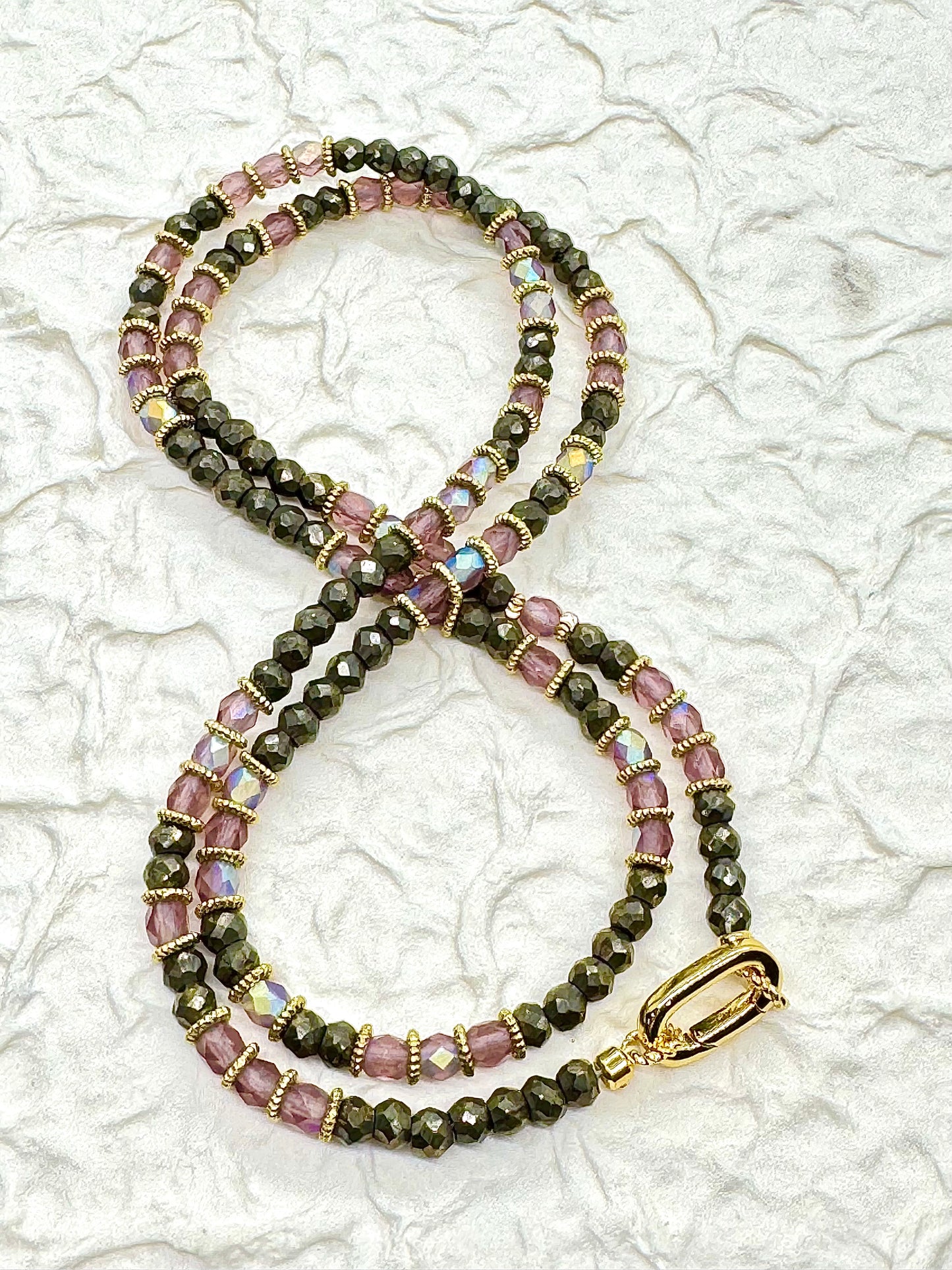 Beaded necklace with black and pink beads on a textured white background