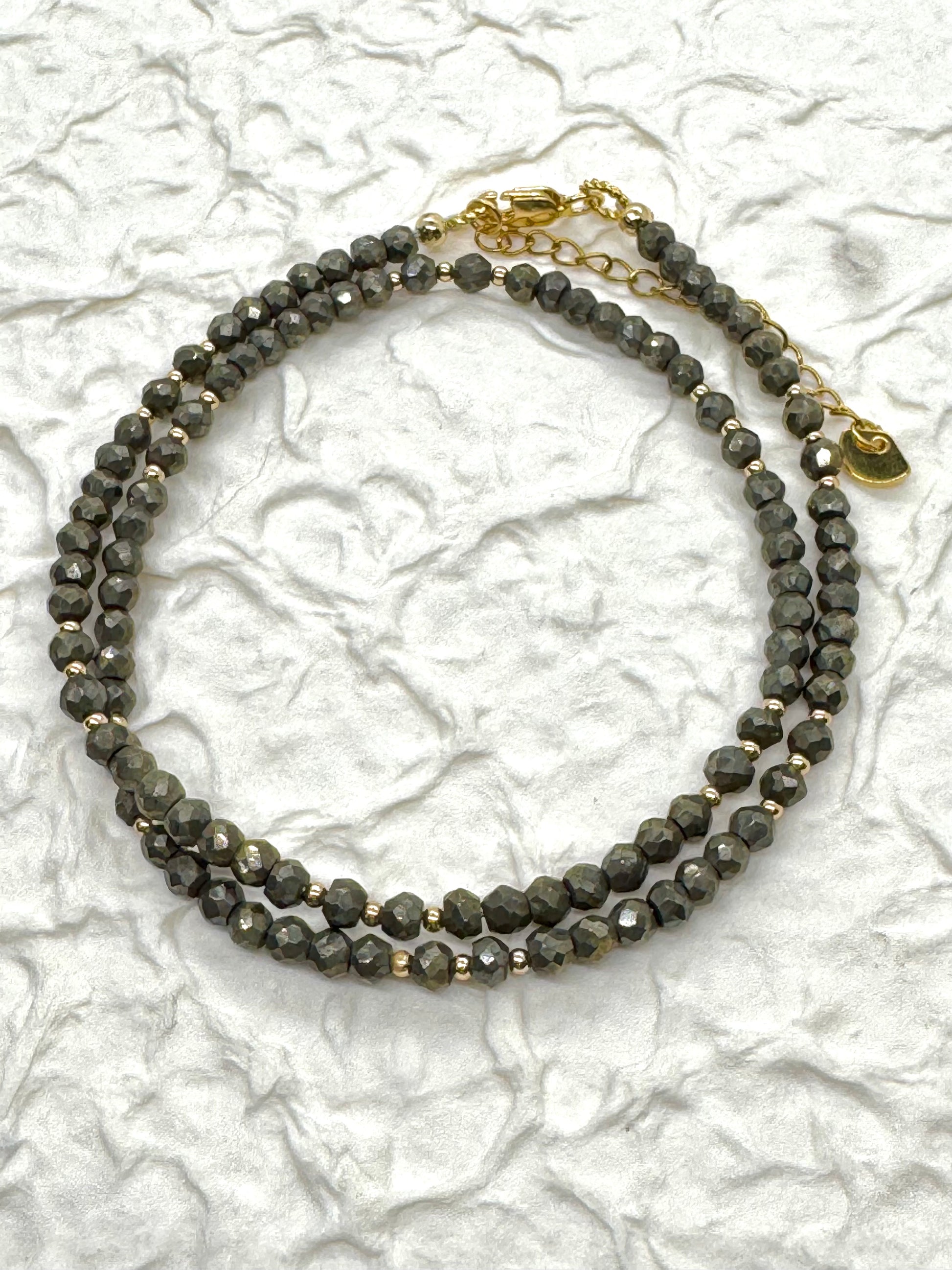 Necklace with gray beads and gold accents on a textured white background