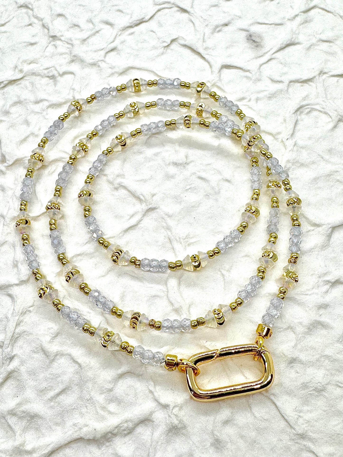 Gold and clear beaded necklace on a textured white background