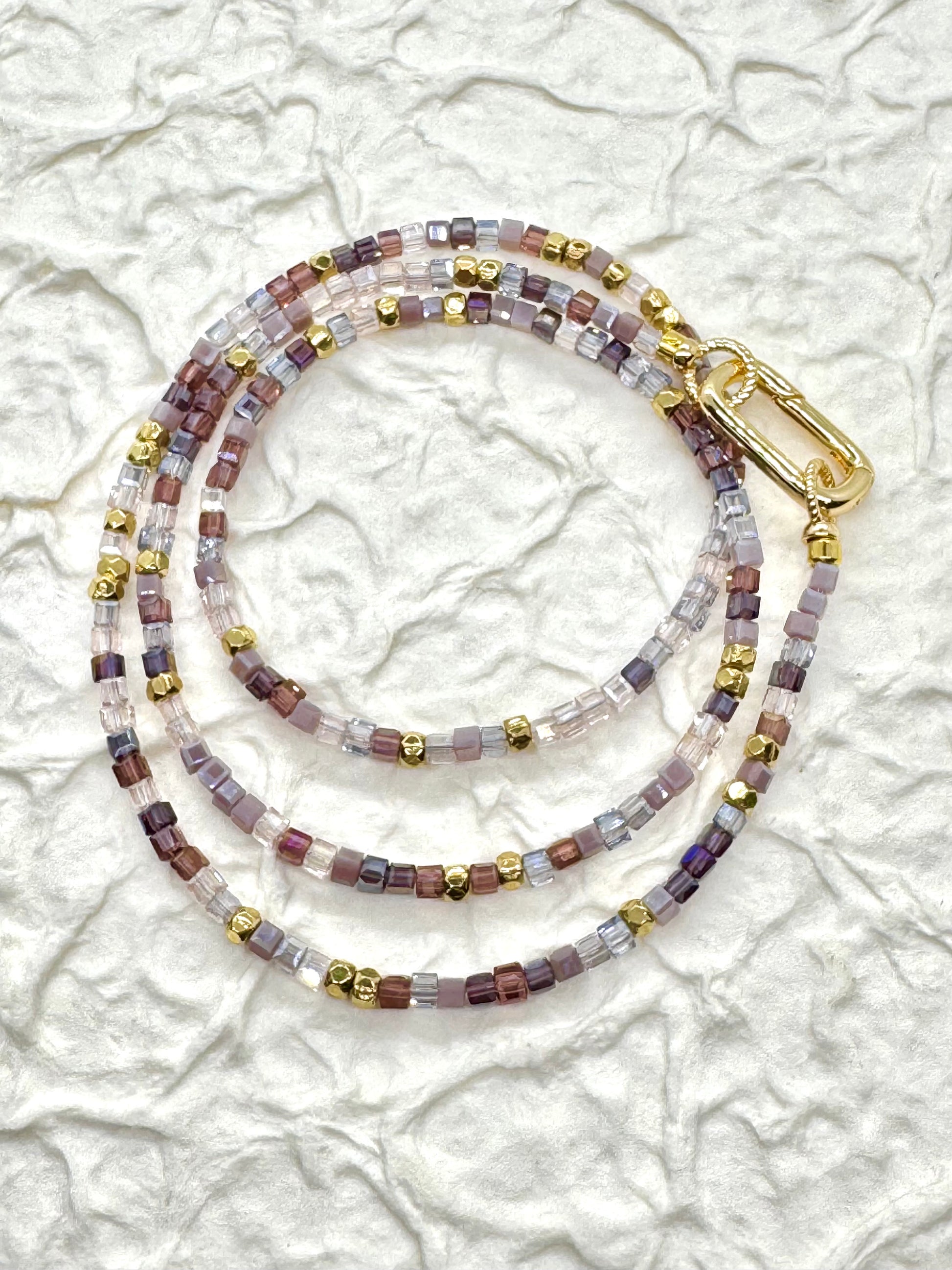 Beaded lanyard with gold clasp on a textured white background