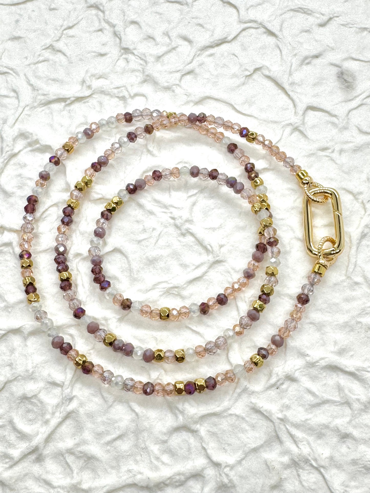 Beaded lanyard with a gold clasp on a textured white background