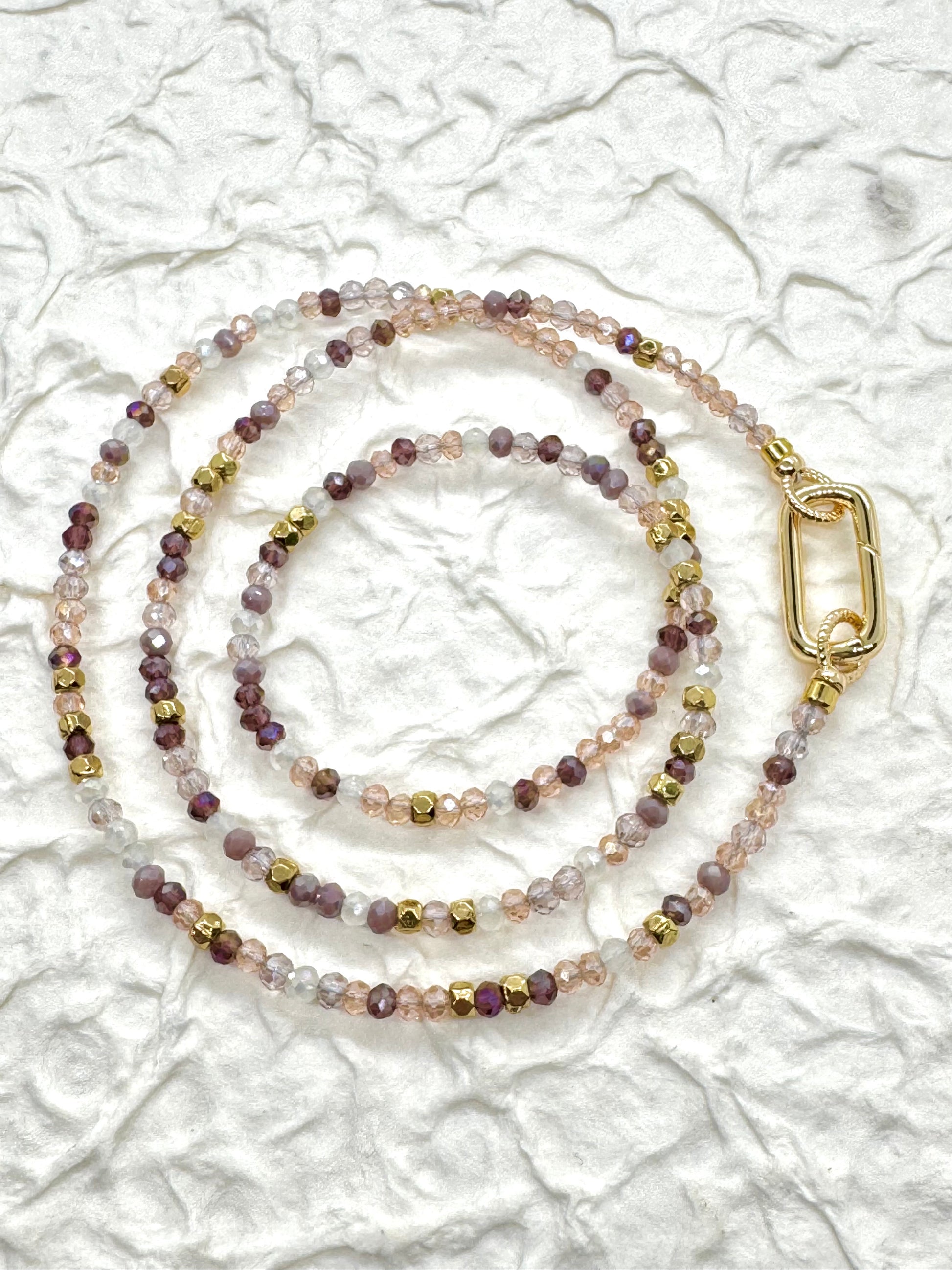 Beaded lanyard with a gold clasp on a textured white background