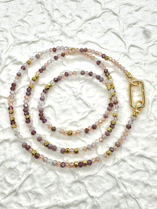 Beaded lanyard with a gold clasp on a textured white background