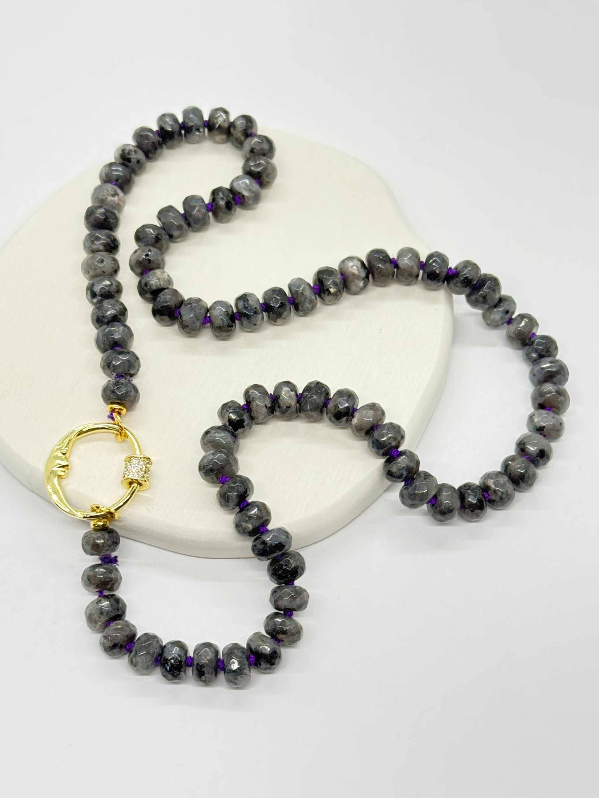 Gray beaded necklace with a gold clasp on a white background