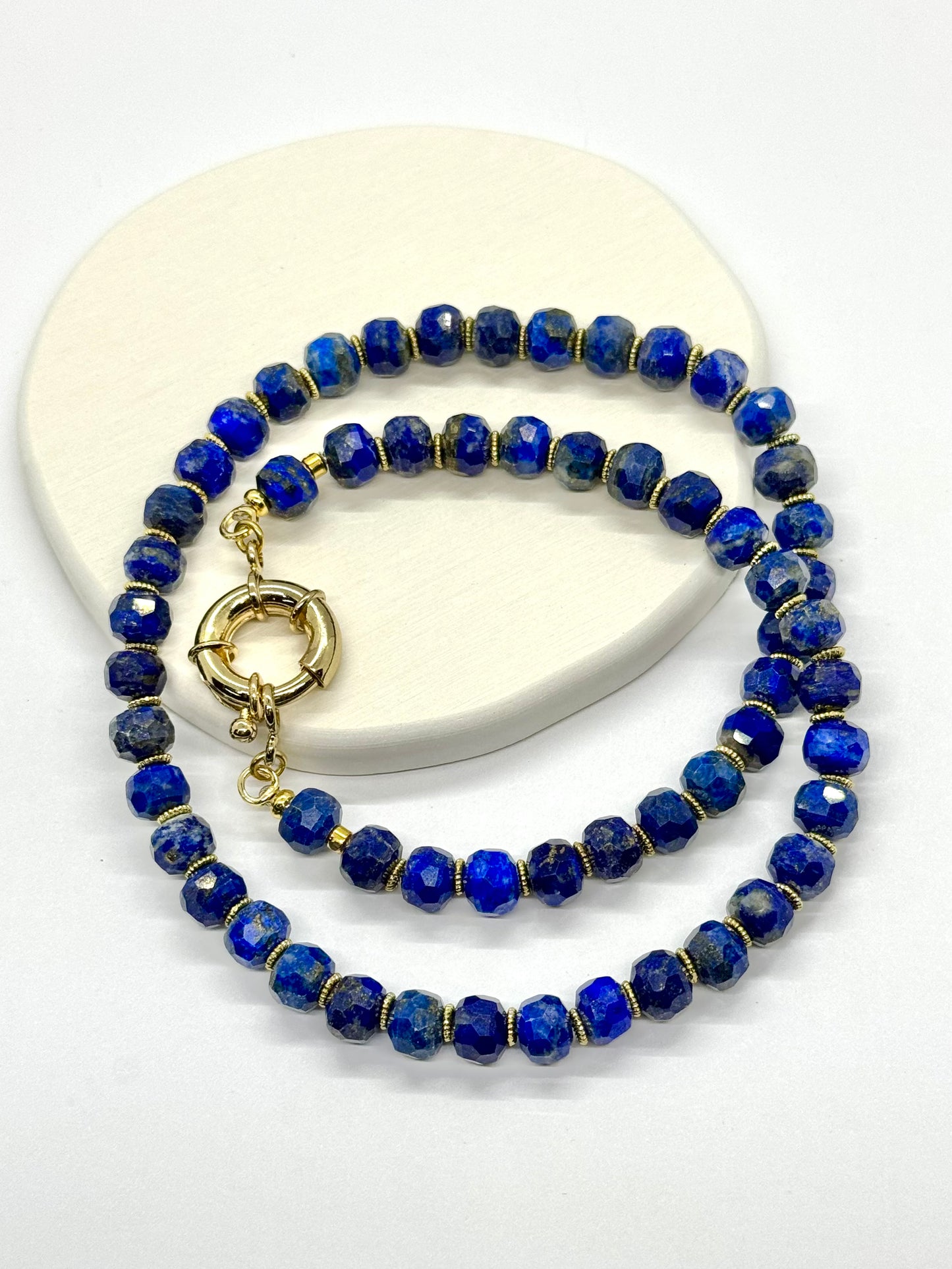 Blue beaded necklace with gold clasp on a white surface
