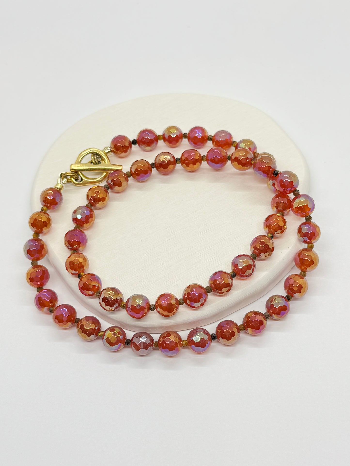 Beaded red necklace with a gold clasp on a white surface