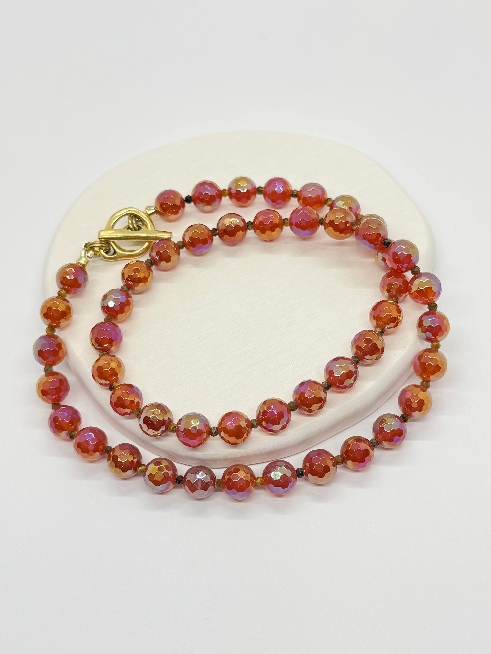 Beaded red necklace with a gold clasp on a white surface