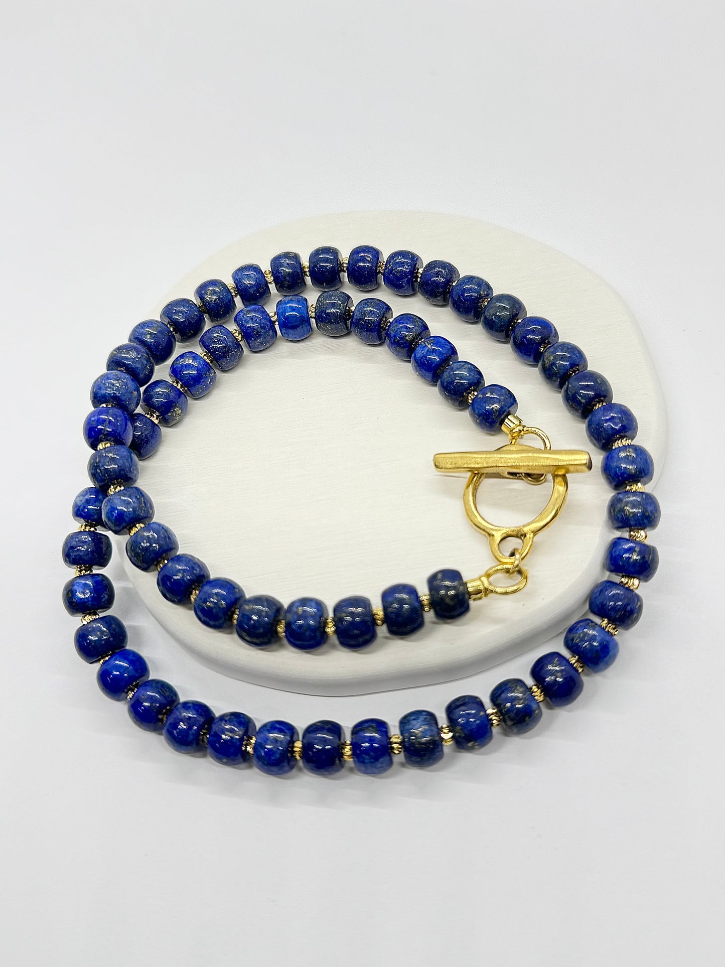 Blue beaded necklace with a gold clasp on a white surface