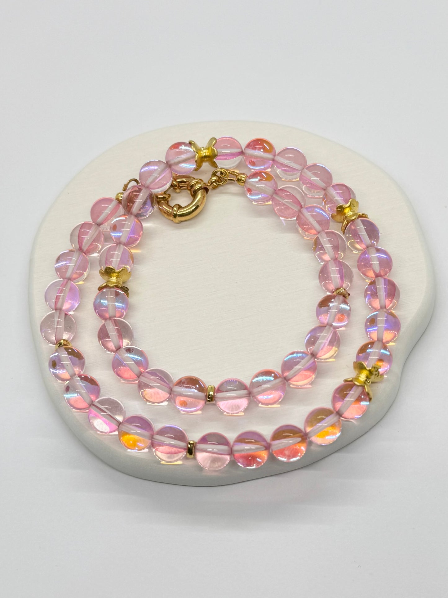 Pink beaded necklace with gold accents on a white heart-shaped stone