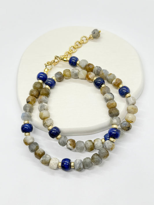 A beaded necklace with blue and gold accents on a white surface
