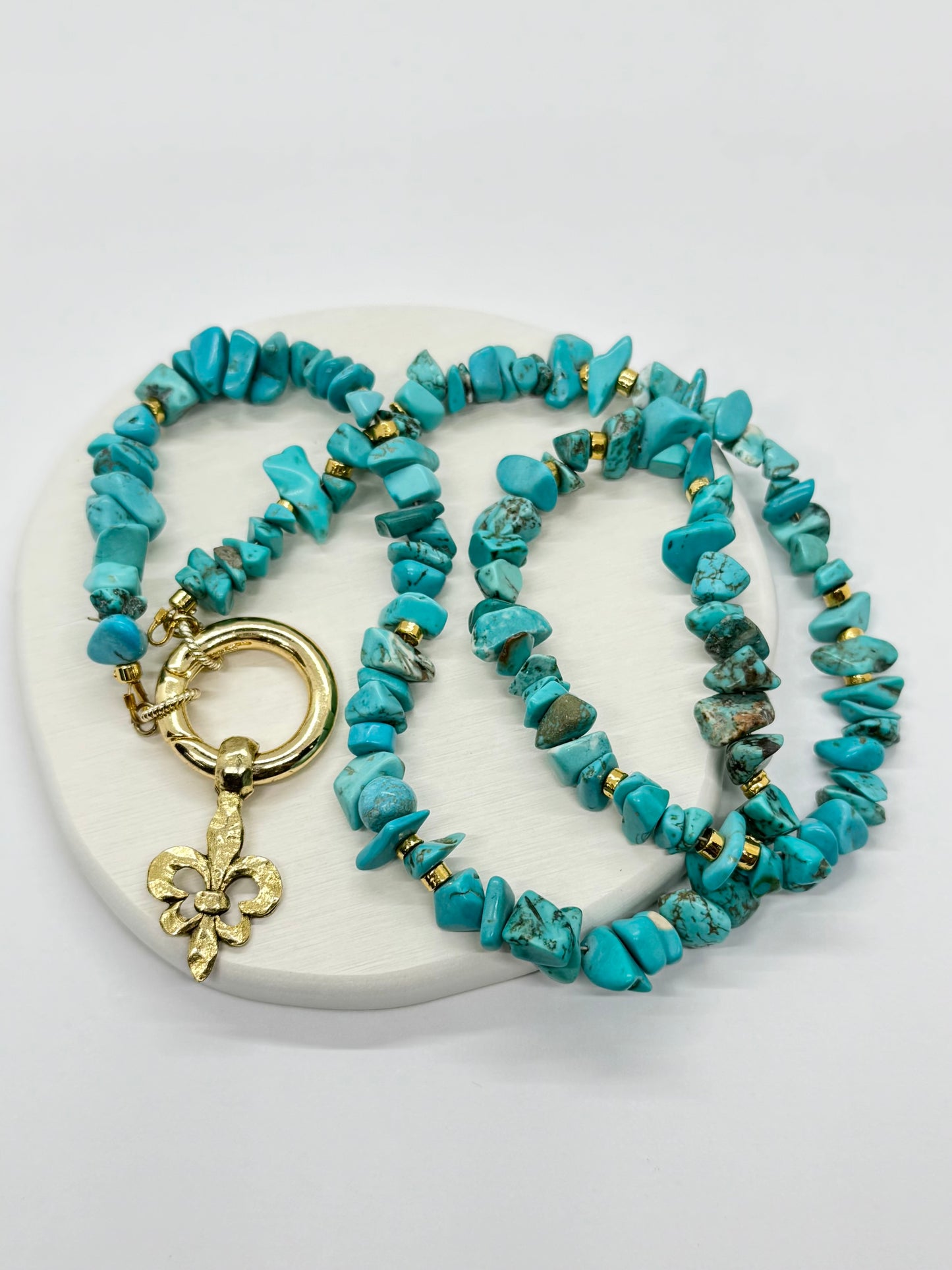 Turquoise beaded necklace with gold clasp on a white surface