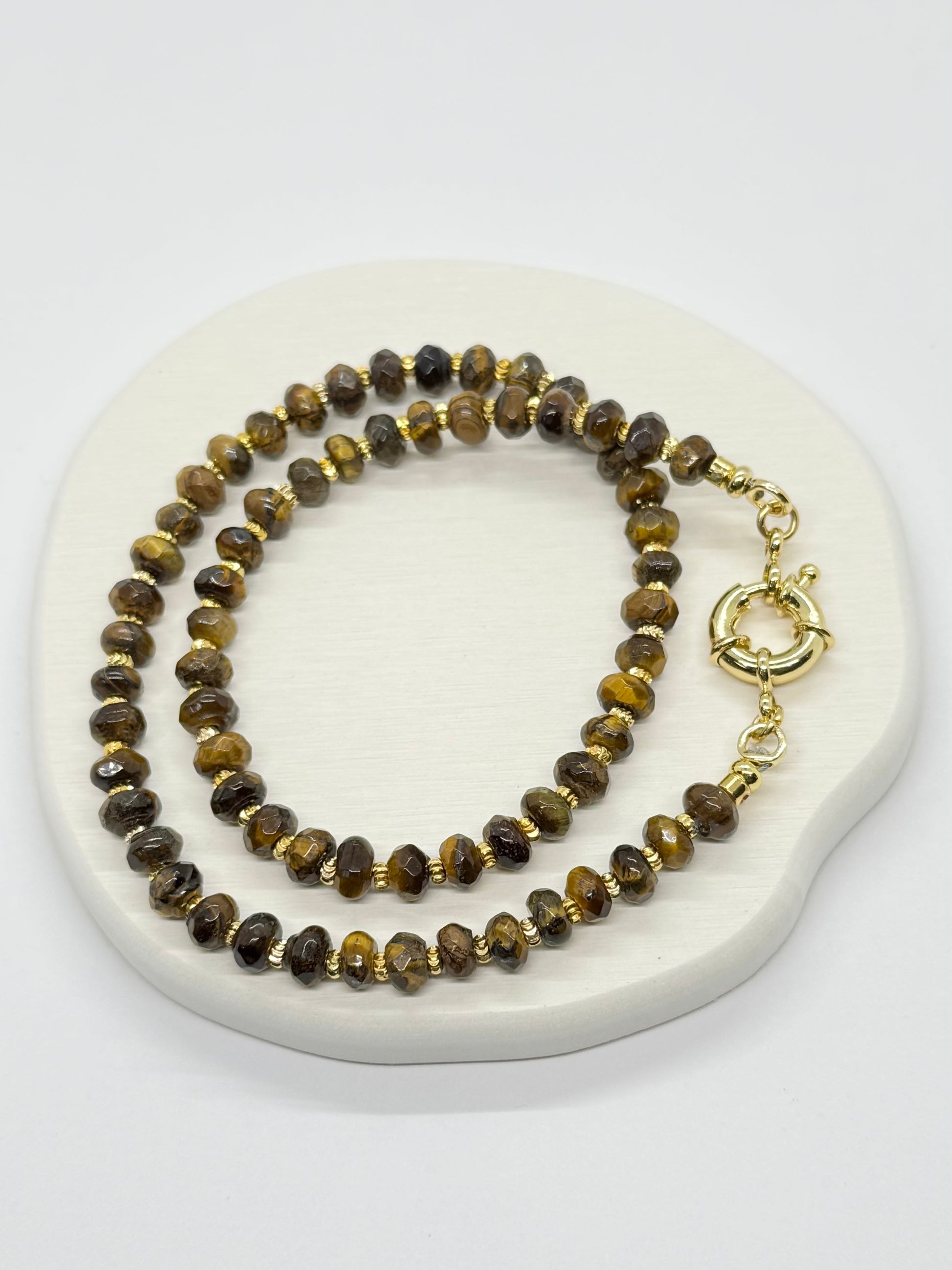Beaded necklace with gold clasp on a white marble surface