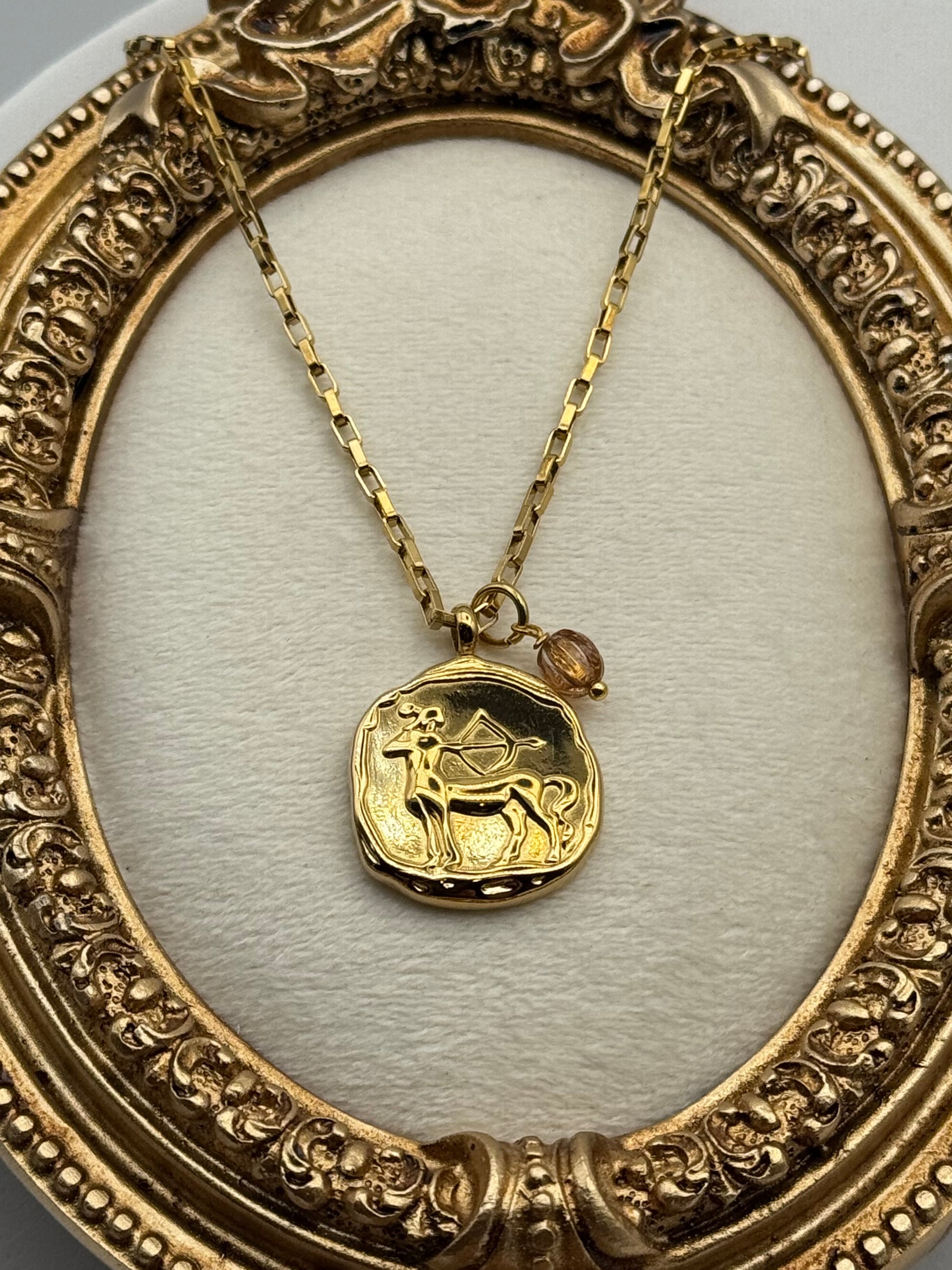 Gold necklace with a zodiac pendant in an ornate gold frame