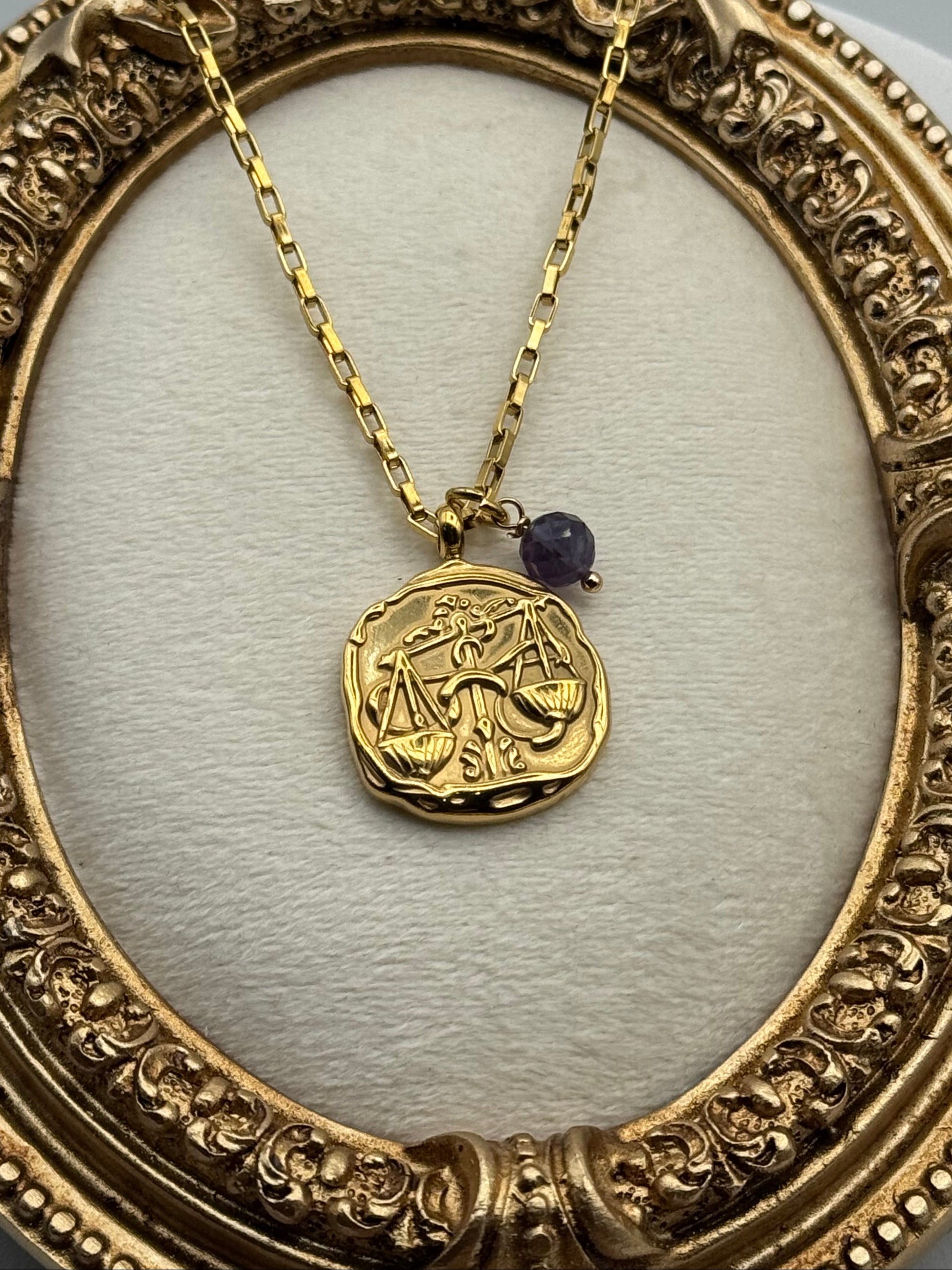 Gold necklace with a pendant featuring a zodiac symbol in an ornate gold frame.