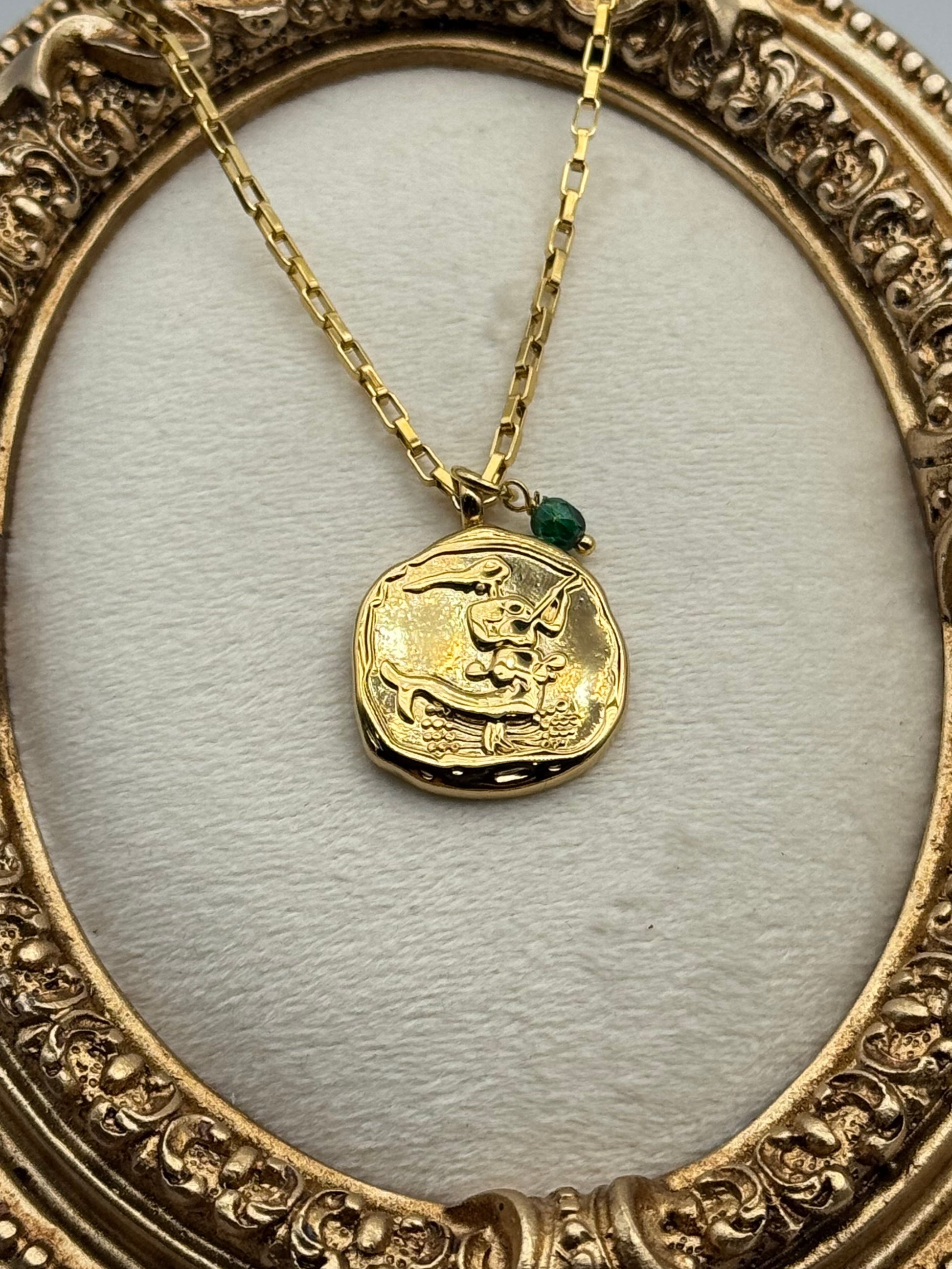 Gold necklace with a coin pendant on a white background