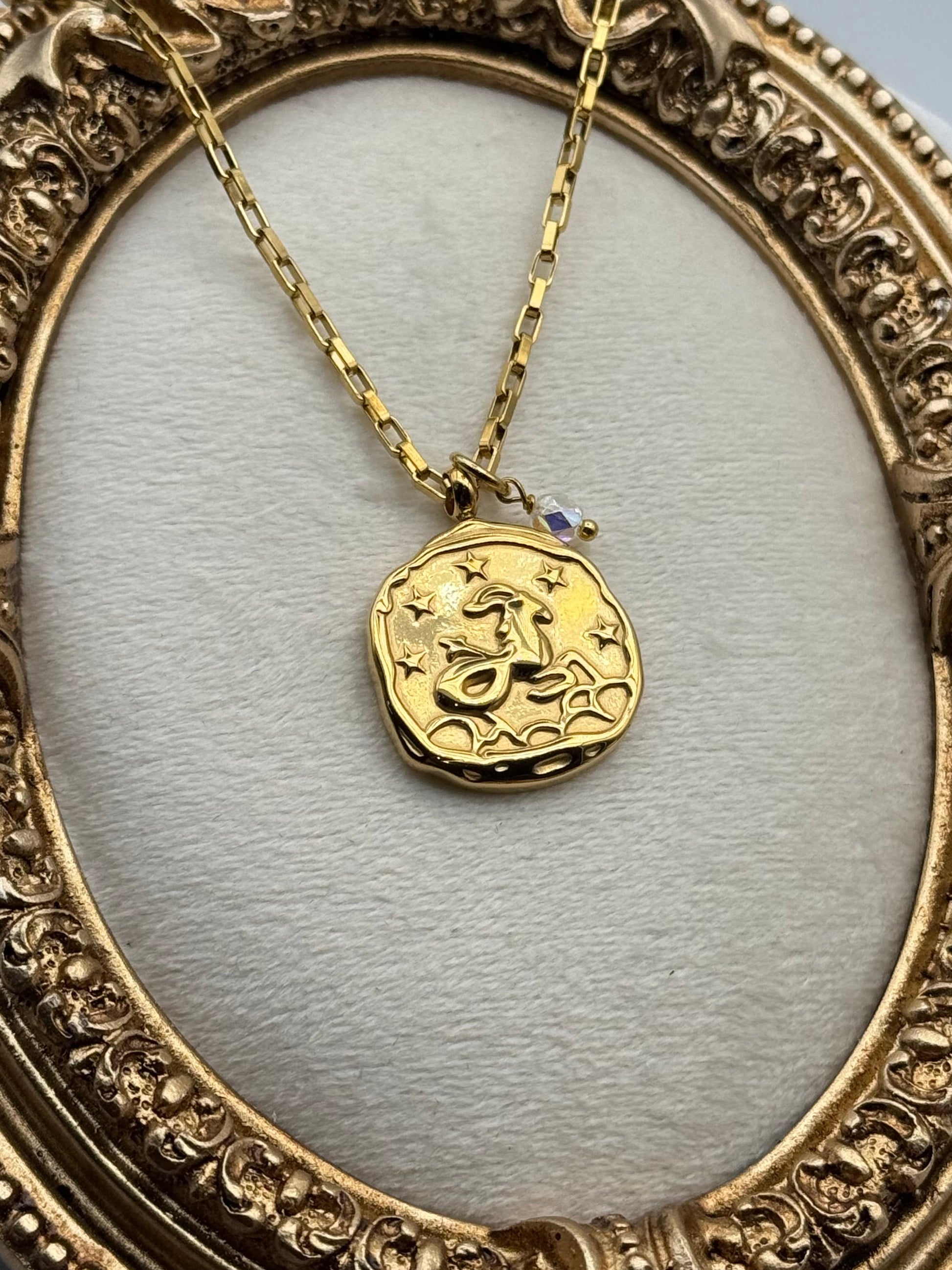 Gold necklace with a round pendant in an ornate gold frame.