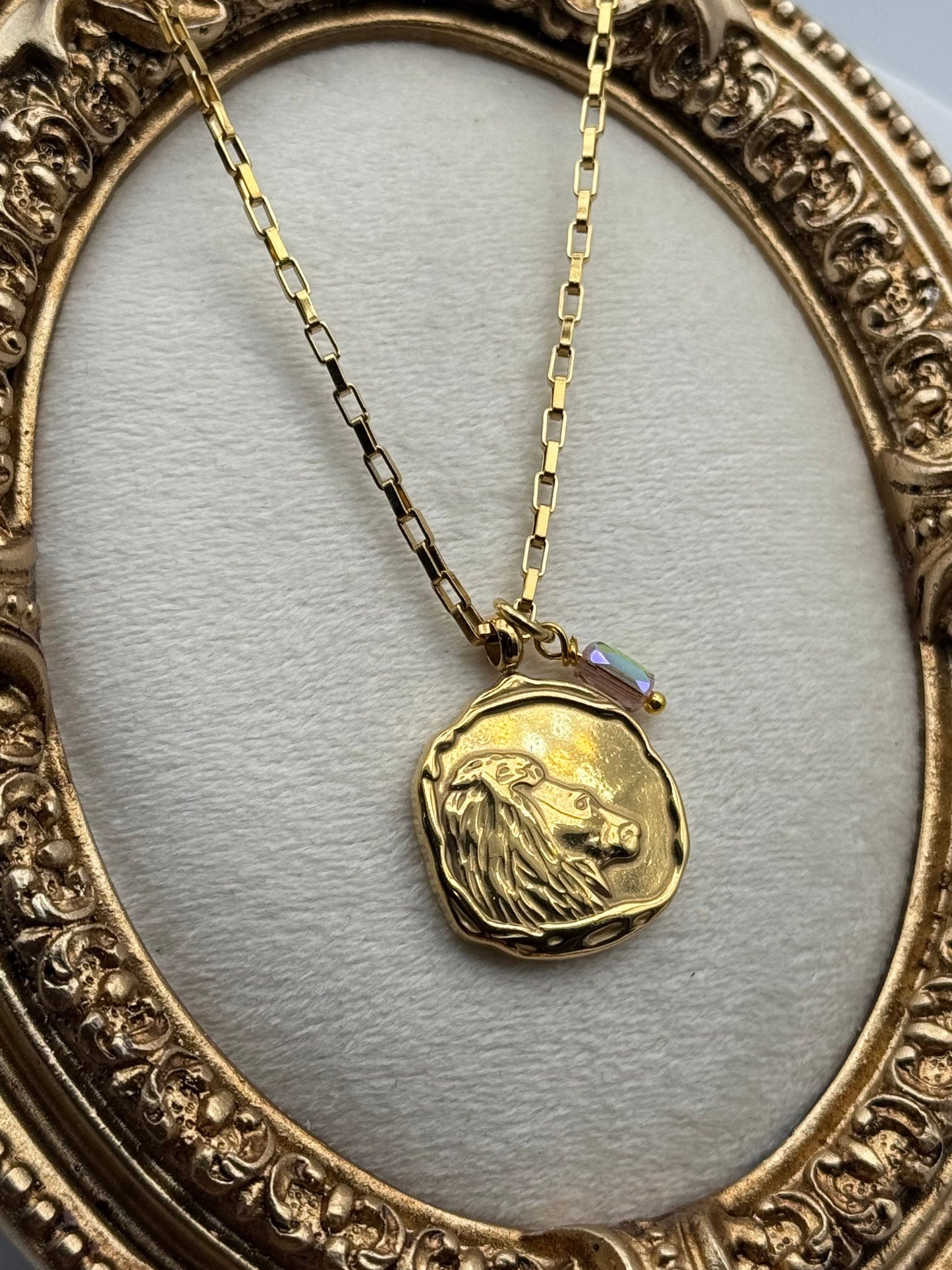 Gold necklace with a pendant in an ornate gold frame