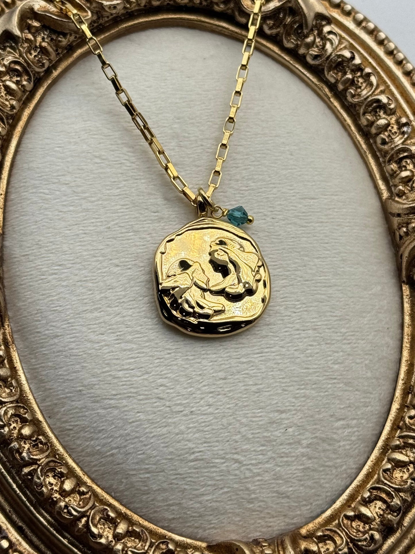 Gold necklace with a pendant in an ornate gold frame
