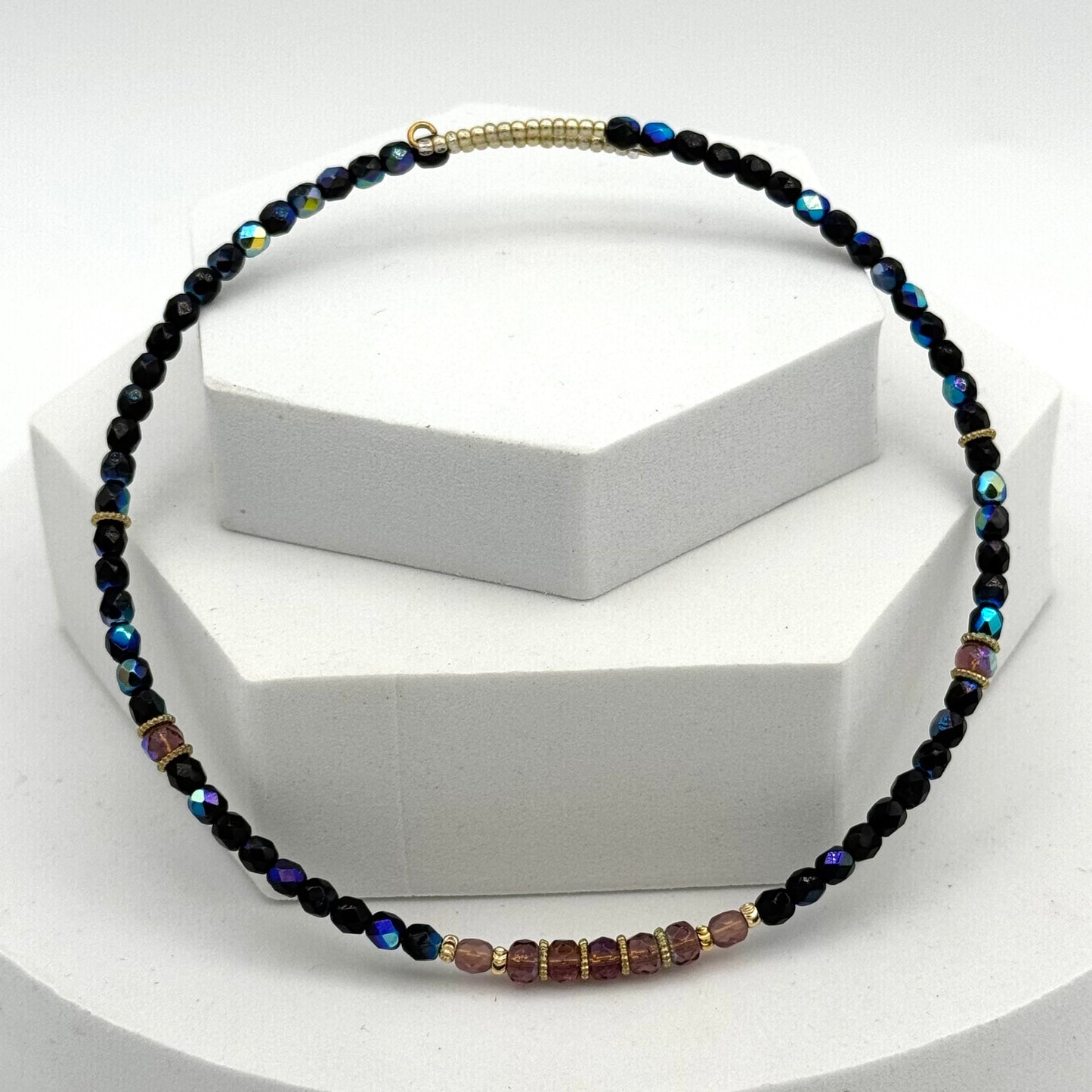 Necklace with black and multicolored beads on a white stand