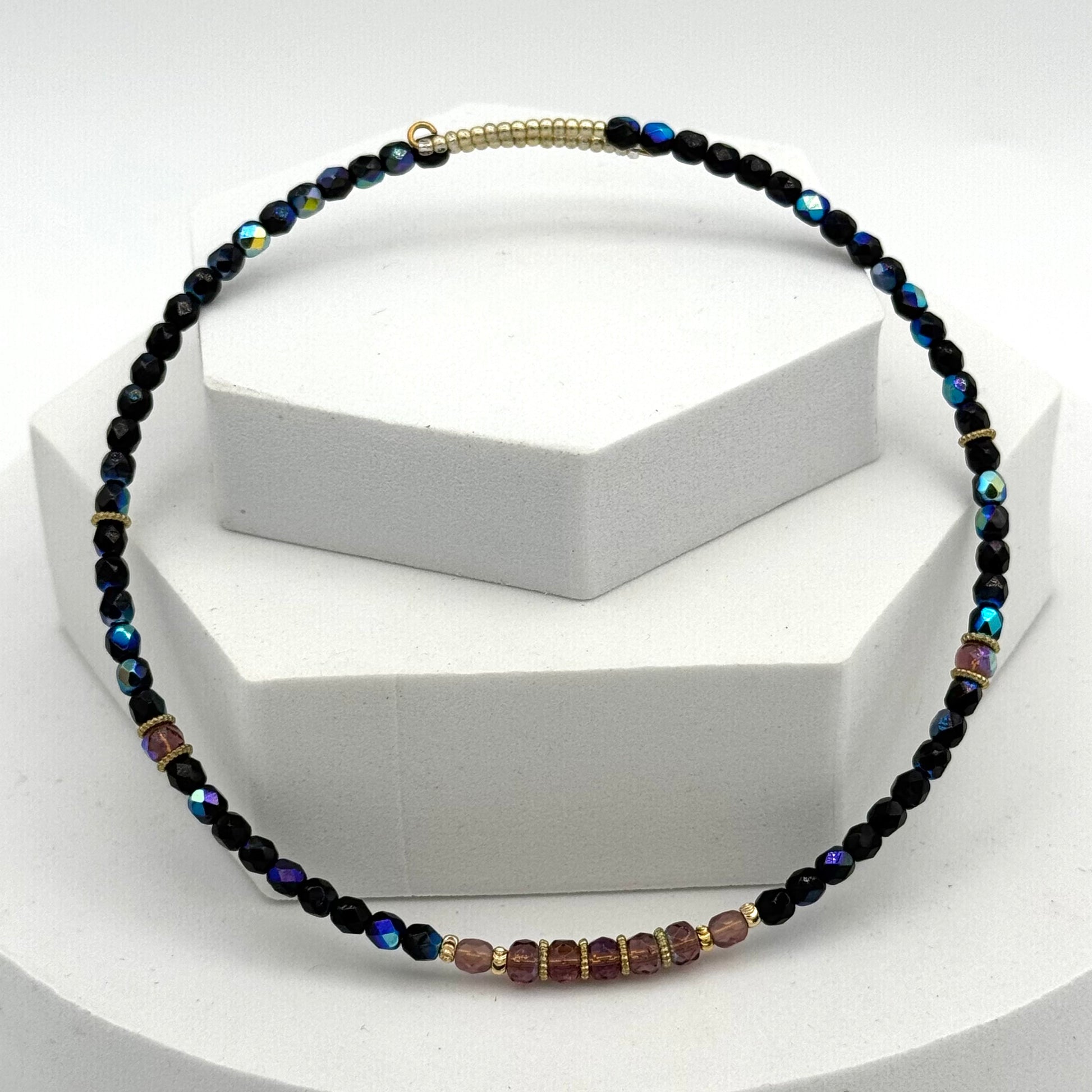 Necklace with black and multicolored beads on a white stand