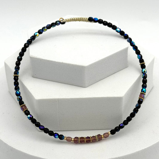 Necklace with black and multicolored beads on a white stand