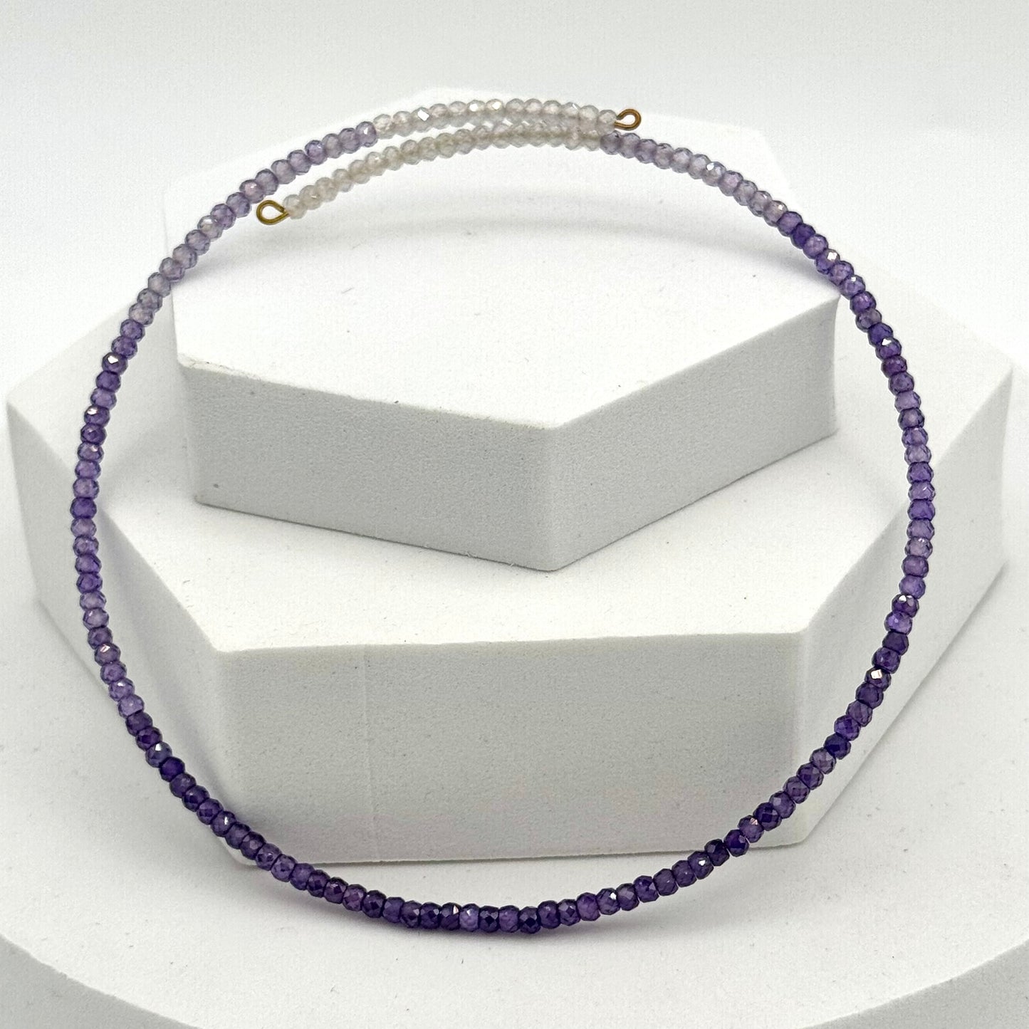 Necklace with purple beads on a white stand