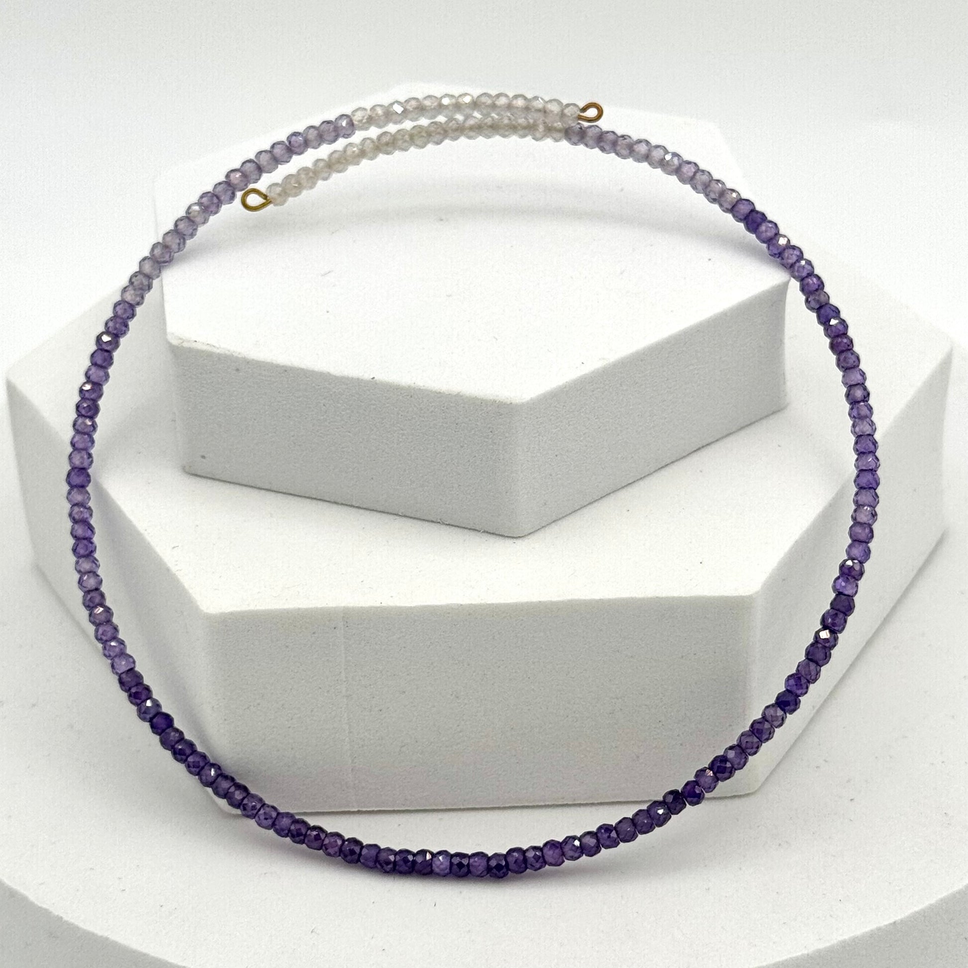 Necklace with purple beads on a white stand